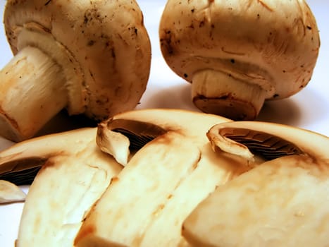 Organic grocery store mushrooms sliced and whole on white background.