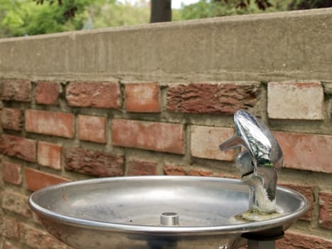 Antique drinking fountain near a brick wall.