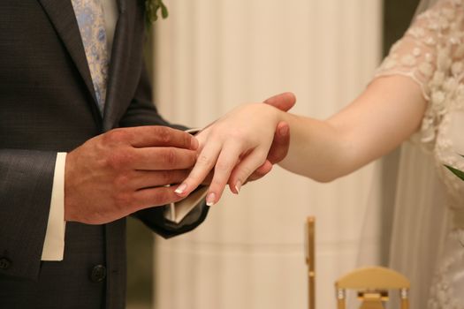 Hands of the groom and the bride during wedding ceremony
