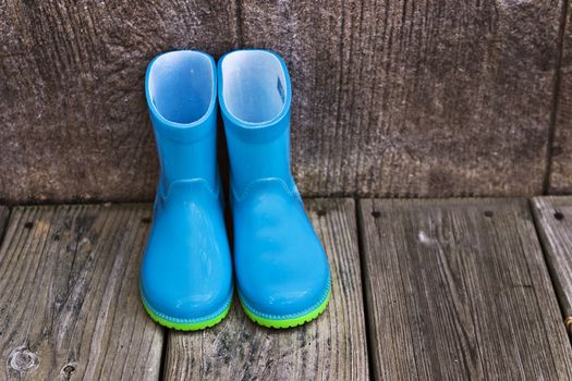 Child's blue rain boots sitting outside