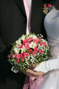 Bouquet of flowers on a background of a dress of the bride and a suit the groom. Used is the soft - objective 