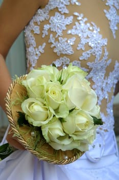 Wedding bouquet from white roses in a hand of the bride