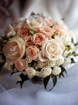 Wedding bouquet from roses and chrysanthemums on a background of a dress