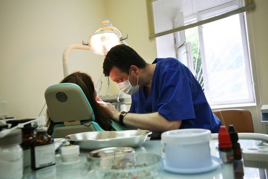 Patient and doctor in stomatological office. The foreground is dim