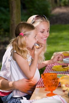 Adorable mother and daughter eating something outside on a summer's day