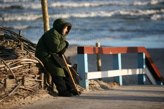 The elderly woman sits on seacoast