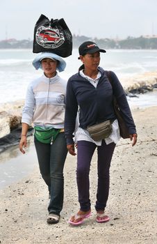 Two Indonesian girls of a saleswoman at coast. Bali. Indonesia