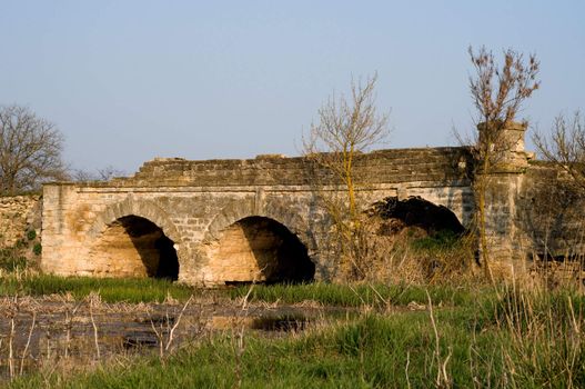 The ancient destroyed stone bridge over the narrow river