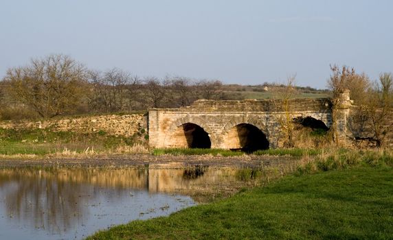 The ancient destroyed stone bridge over the narrow river