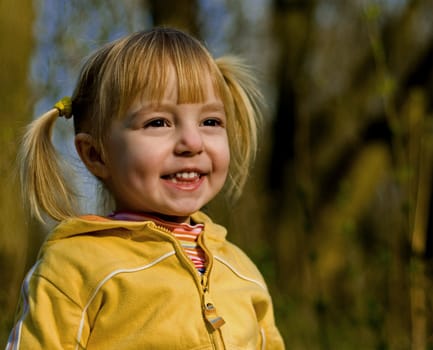 The little girl in spring park looks at a sunset