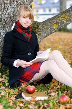 Young student girl is studying outside near the tree