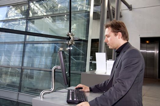 A young executive is standing and using the computer in the  in a business lounge