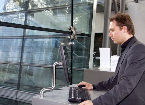 A young executive is standing and using the computer in the  in a business lounge