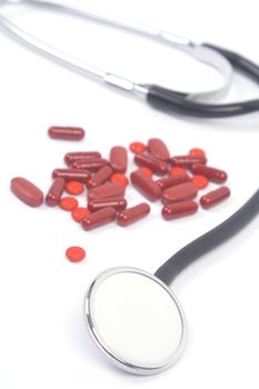 Medicines and stethoscope on white background, close-up