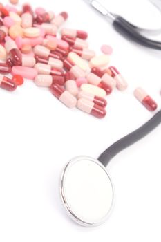 Medicines and stethoscope on white background, close-up