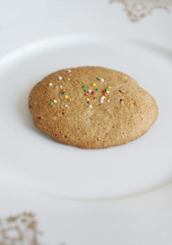 Cookie on the plate strewed with multicolored dots