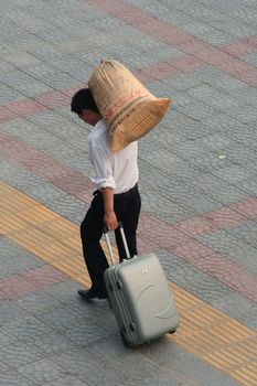 Chinese man carrying his luggage and a paper bag (with Chinese characters) in the street of Xi'an