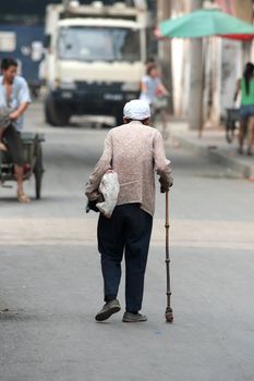 Elderly chinese woman walking with her cane in a street (hutong) of ancient Beijing - Peking - China