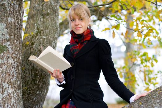 Young student girl is studying outside near the tree