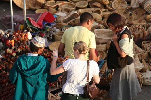 Tourists speaking with craftsmanships retailers about his products in "Place des Epices" market in Marrakech medina in the ancient town - Morocco