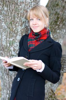 Young student girl is studying outside near the tree