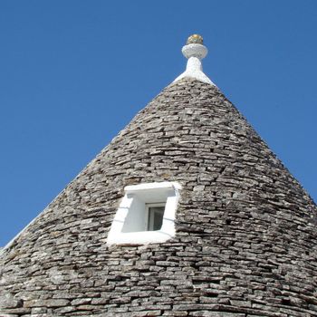 conical roof of trullo house in Apulia, region in Italy. Trulli are local,traditional Apulian stone dwelling with a conical roof. They may be found in the towns of Alberobello, Locorotondo, Fasano, Cisternino, Martina Franca and Ceglie Messapica.