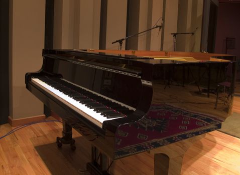 Grand piano in large recording studio with microphones