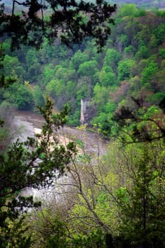 Image of an old abandoned power mill along a small river taken from the top of a hill in the forest.