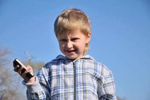 little boy is standing and holding a mobile phone