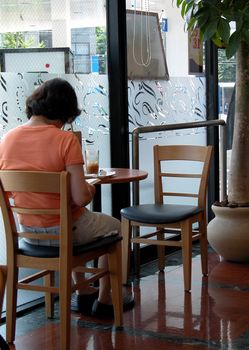 a woman in a coffee bar sitting and reading a magazine          