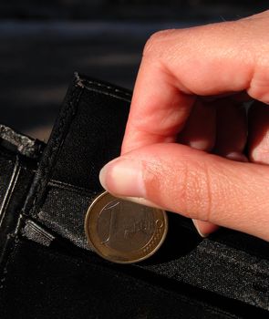 woman fingers inserting a 1euro coin in a man wallet.          