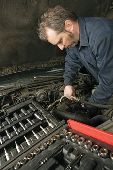 A mechanic repairing an engine of an old car.

