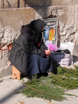 Old woma selling flower in a very old and poor street.          