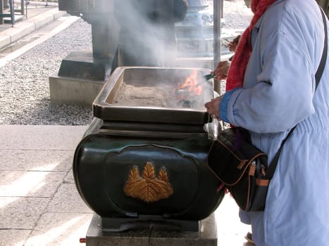 Detail of some believers burning incences at a Buddhist Japanese temple in Kyoto          