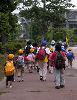 Schoolchildren group walking in a park together with their educators.Useful image to include it in a "Back to school" design         