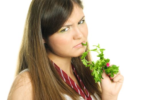 portrait of an unhappy beautiful brunette girl eating fresh green parsley