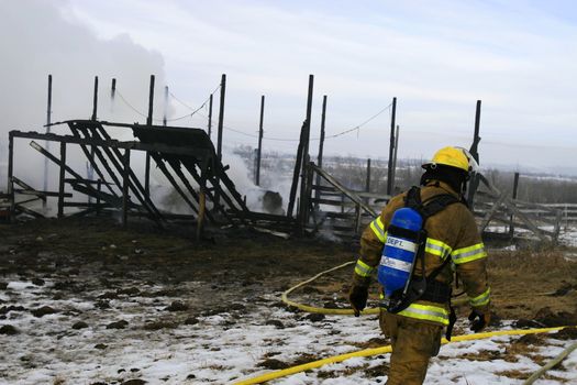 A firefighter cleana up after putting out a barn fire.
