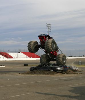A monster truck jumps over cars