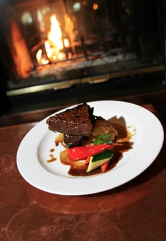 A Bison Steak dish, in front of a fireplace.