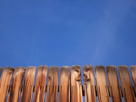 A wooden fence stands in front of a clear, blue Colorado sky.