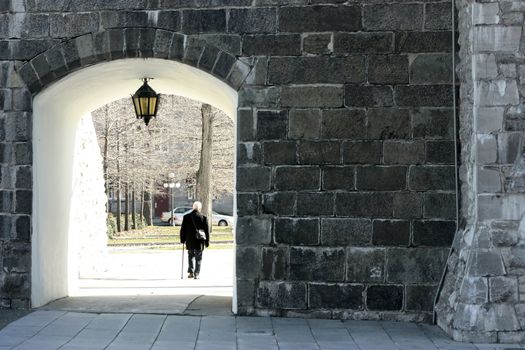 a man is walking under a passageway under a big old city gate