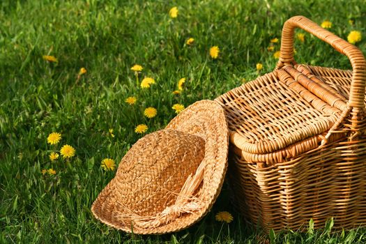 Summer hat and wicker basket on the grass