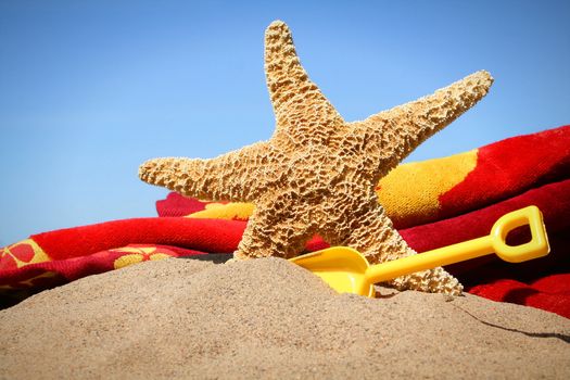 Big starfish in the sand with shovel and beach towel