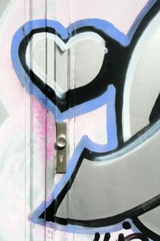 Detail of an illegal graffiti sprayed on an outside door. The doorknob is right below the heart. Love metaphor.