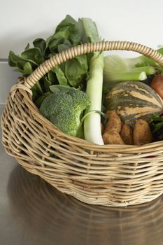 Still life of vegetables on stainless steel bench in wicker basket