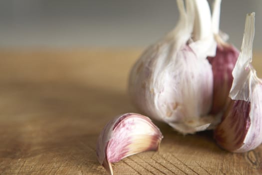 Macro image of fresh garlic on rough wooden chopping board Shallow focus.