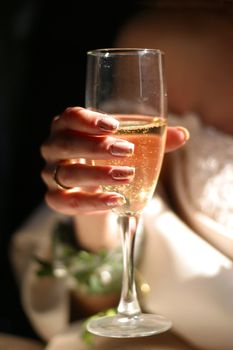 Glass of champagne in a hand of the bride
