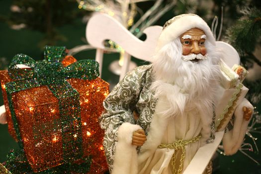 Toy Santa Claus with gifts on white sledge