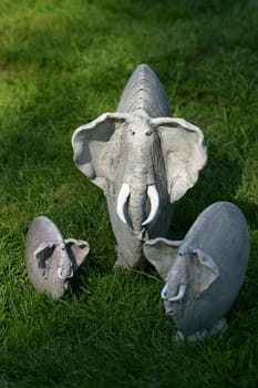 Three clay elephants on a grass