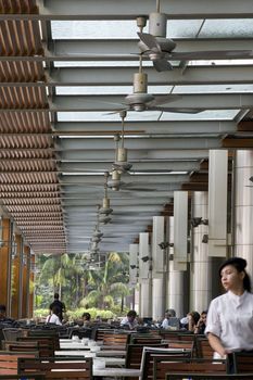 A colonial style cafe in Kuala Lumpur, Malaysia. In the background of the open air cafe, you can see the palm trees, which further illustrates the openness of the establishment.